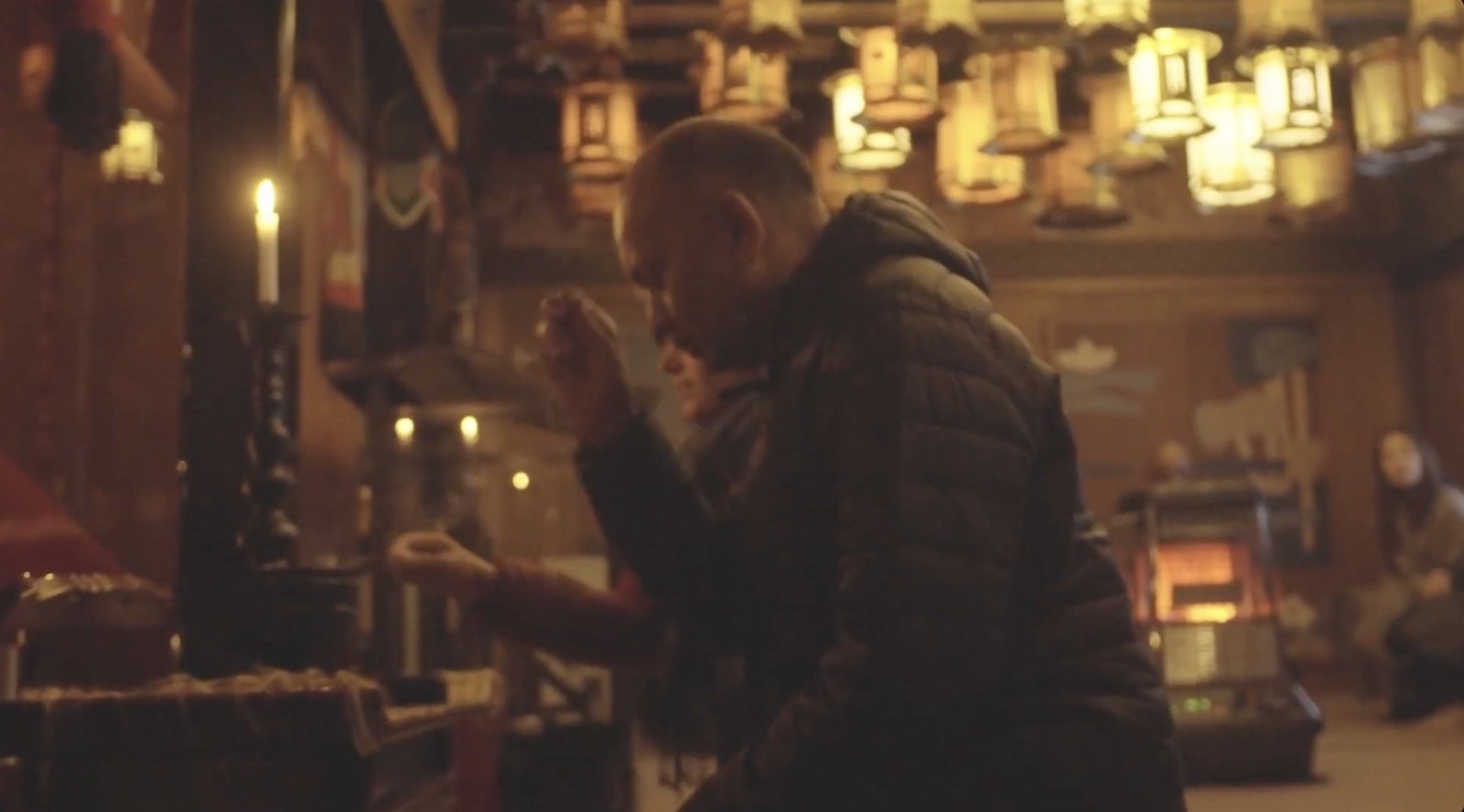 A moment of prayer in the warm light of a temple interior. KUNI film archive, 2024.