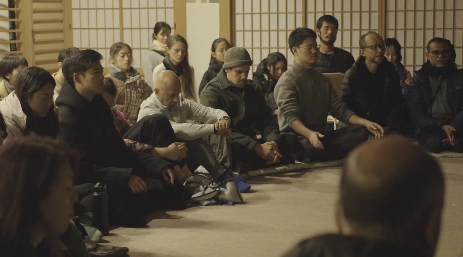 People sitting together in a tatami room, listening in silence.