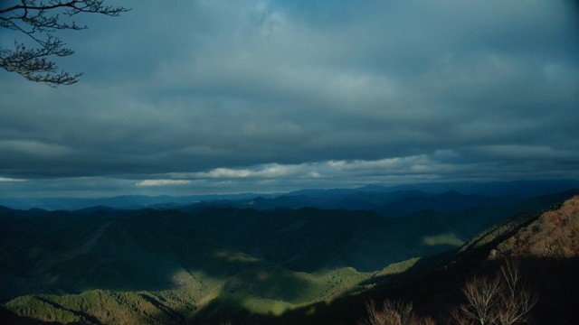 Weather and moving light over layered mountain ridges