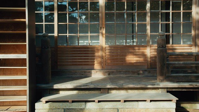 An empty wooden temple threshold held between shadow and sunlight