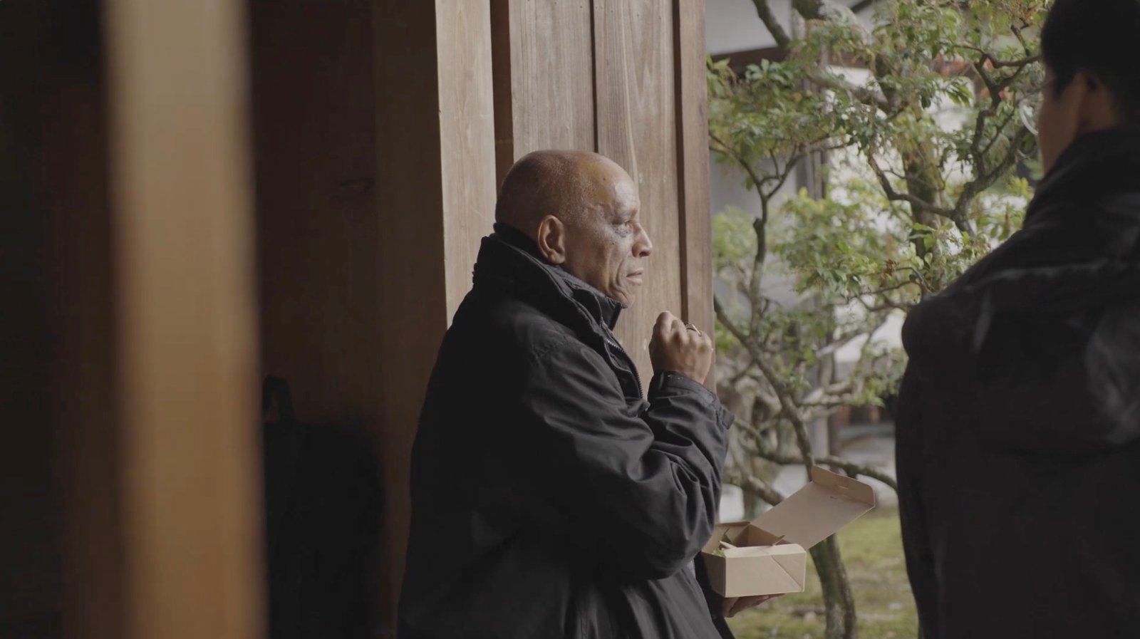 Orland Bishop in conversation on a veranda overlooking a garden.